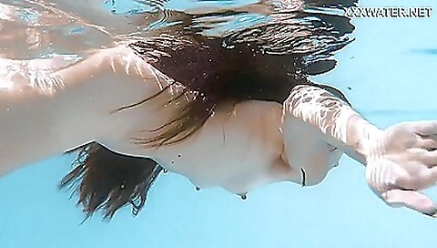 Slender brunette babe swims in the ocean and enjoys